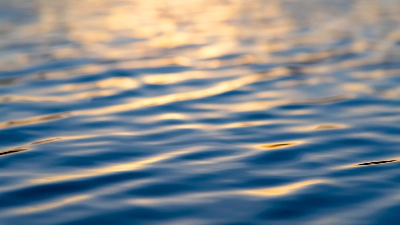 Wasseroberfläche mit sich spiegelndem Licht auf leichten Wellen