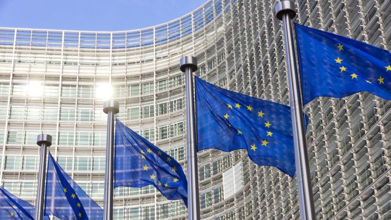 Bild des EU Kommissions Gebäude in  Brüssel mit Europa Fahnen im Vordergrund